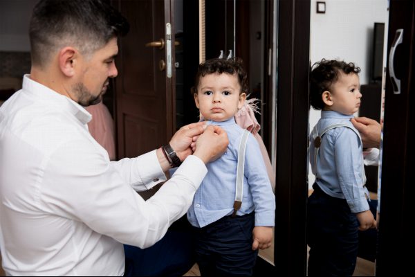 Vater hilft seinem Sohn, sich für die kirchliche Zeremonie anzuziehen