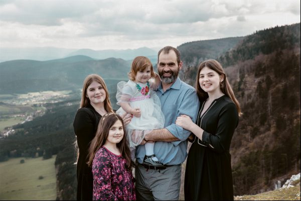 Ein Vater und seine vier Töchter lächeln im Naturpark Hohe Wand