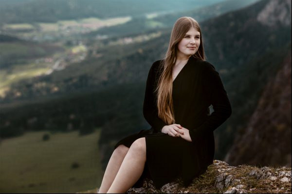 Ein Mädchen posiert auf dem Gipfel der Hohen Wand, Naturpark mit dem wunderschönen Tal als Hintergrund.