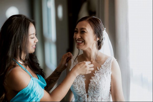 Brautjungfer lächelt der Braut an ihrem Hochzeitstag zu Braut und ihre Brautjungfer lachen